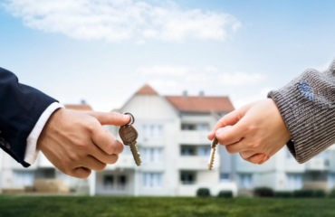 a-young-couple-or-family-standing-in-front-of-a-new-house-or-apartment-holding-keys-in-their-hands