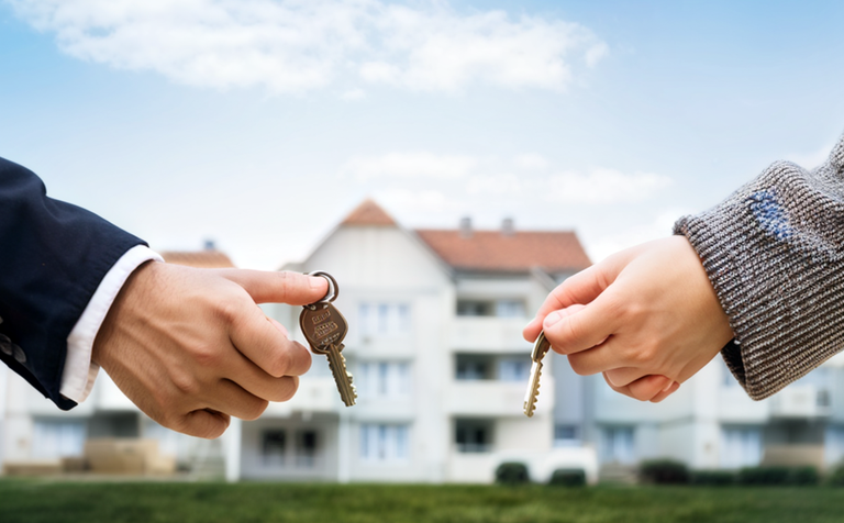 a-young-couple-or-family-standing-in-front-of-a-new-house-or-apartment-holding-keys-in-their-hands